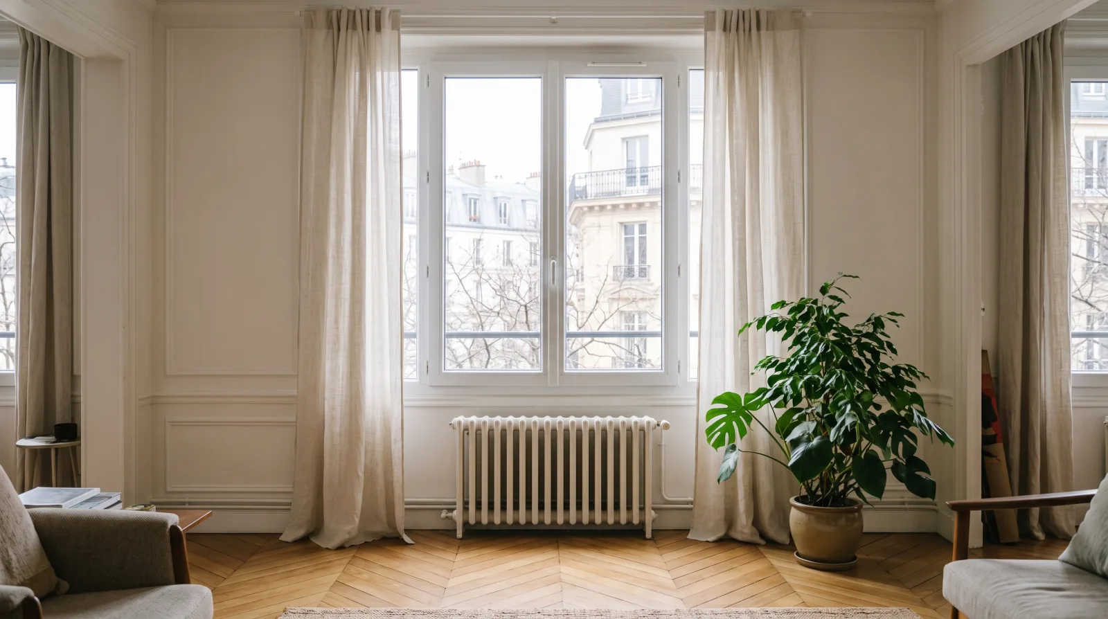 Fenêtre PVC blanche à double vitrage dans un séjour lumineux avec rideaux de lin et parquet